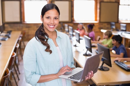 bigstock-Pretty-teacher-using-laptop-in-85247846